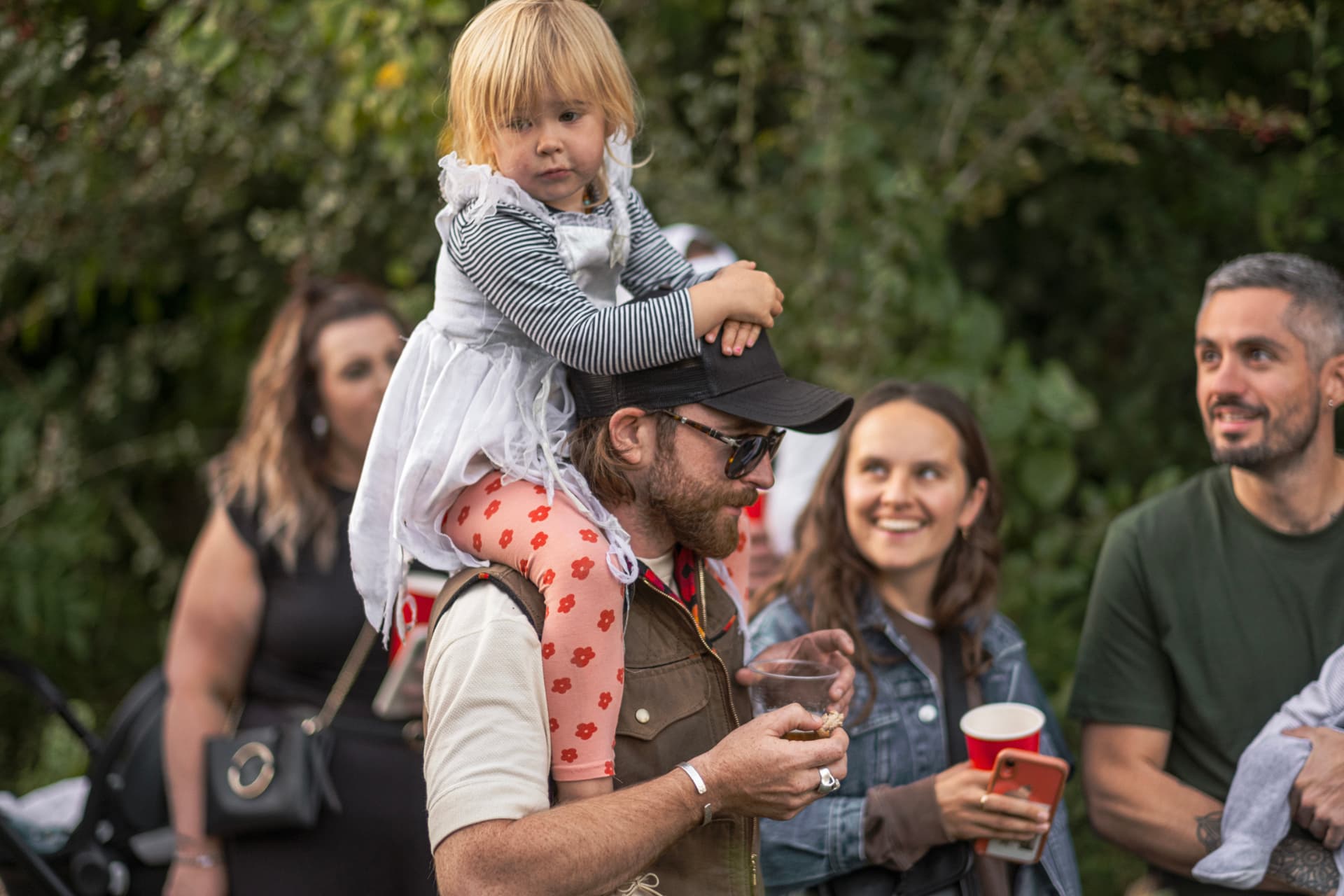 A child on their parent's shoulders in the crowd at the garden opening