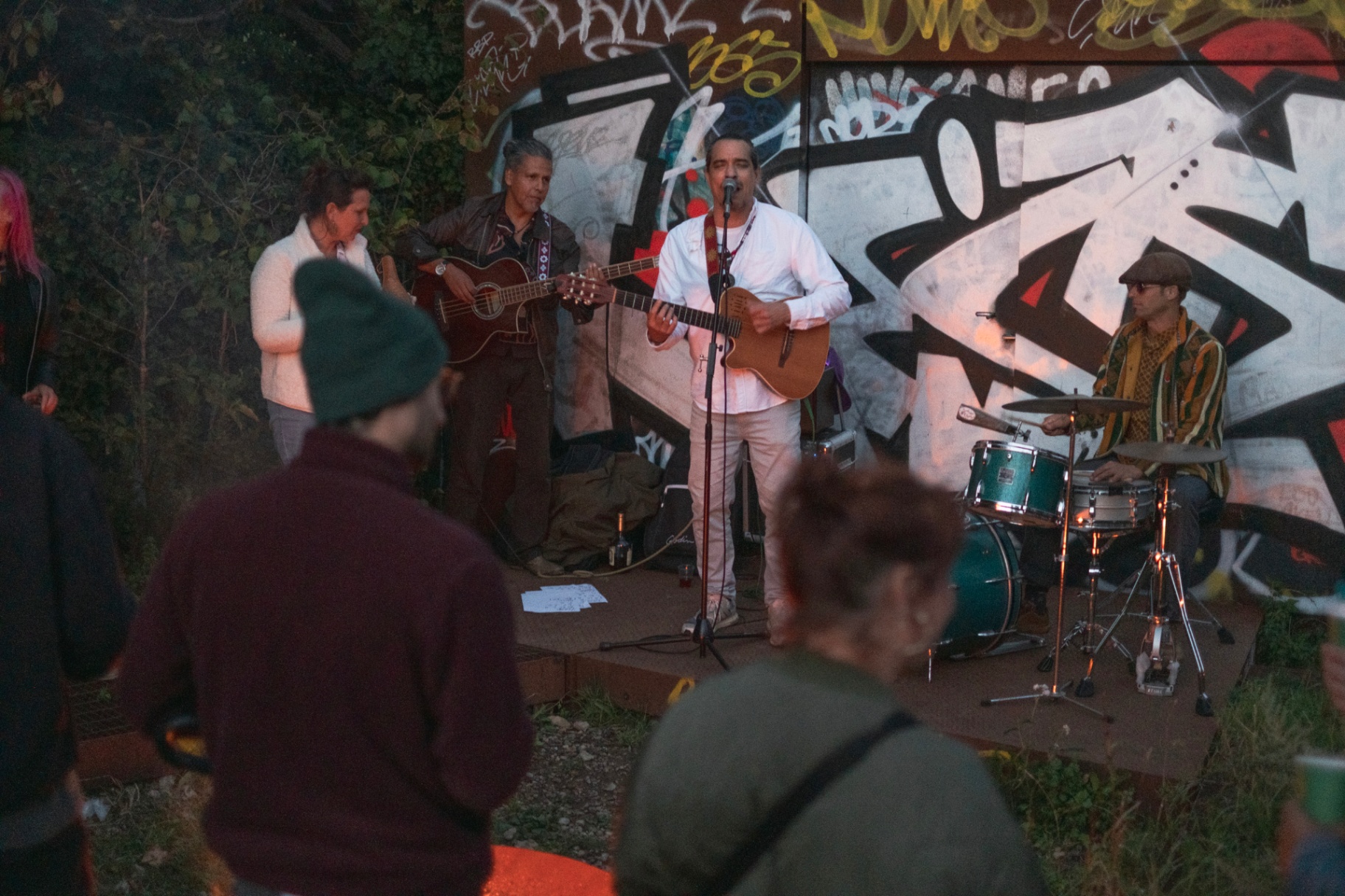 Live band performing against the graffiti wall as the sun sets on Markfield Rd Festival 2025.