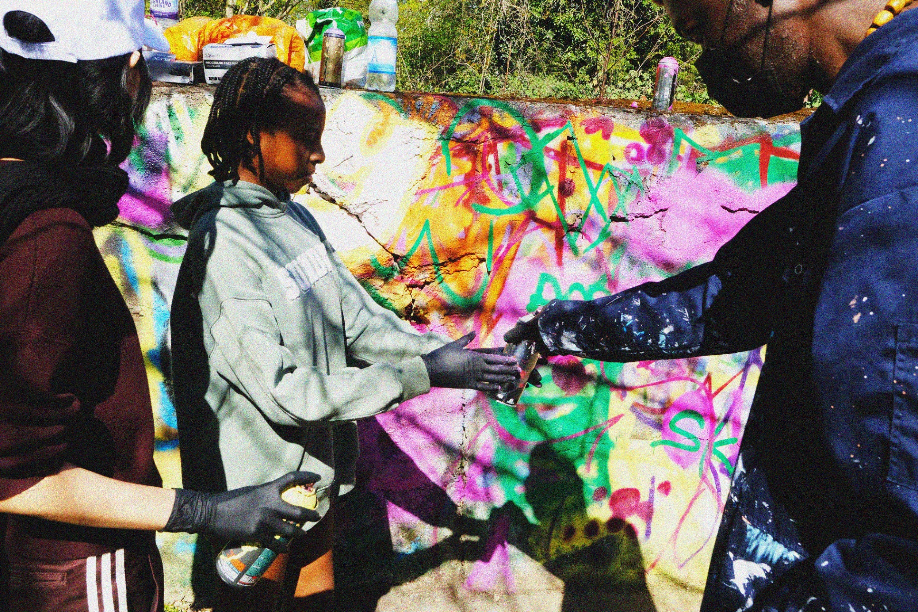 A spray can being passed between hands at the wall.