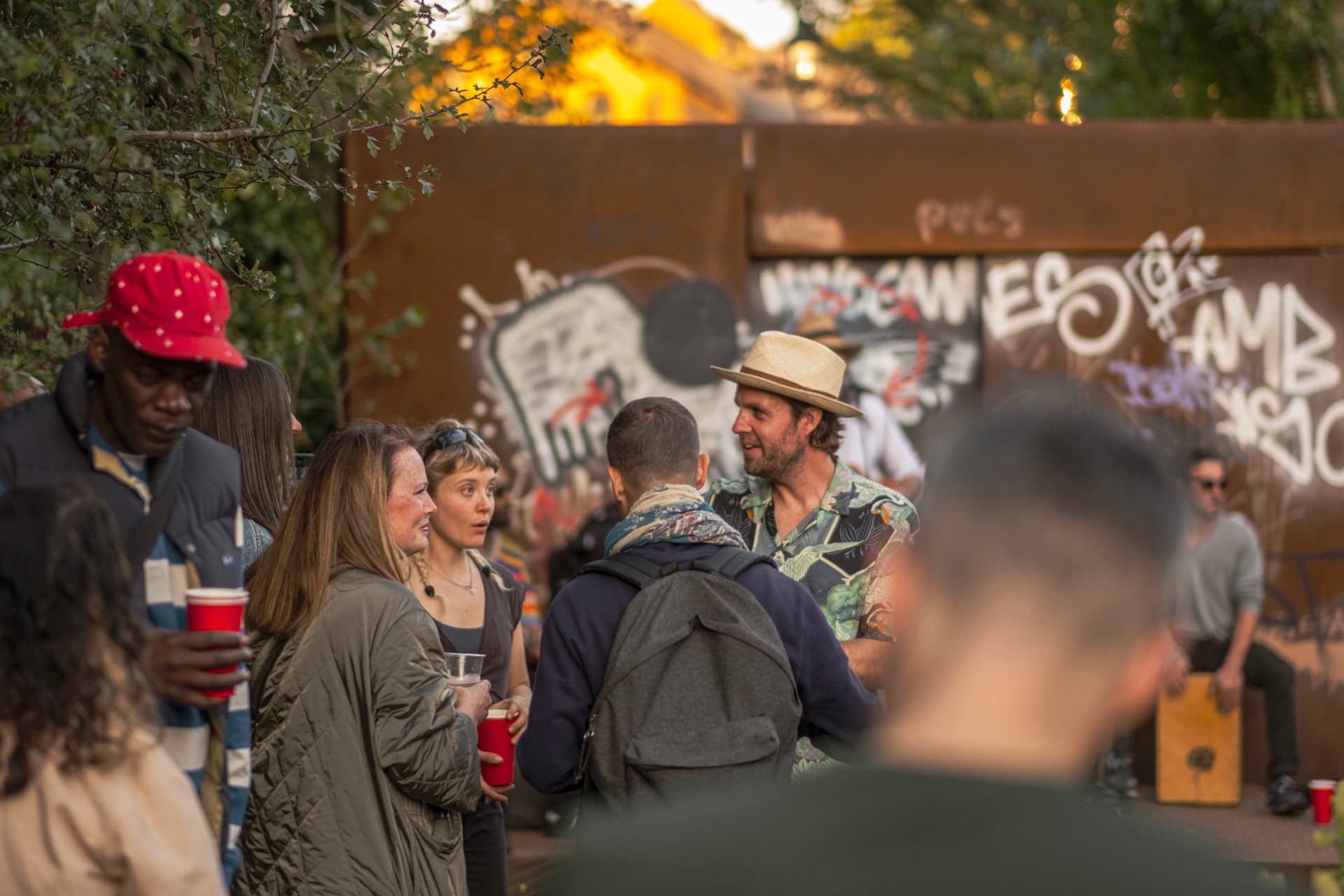 Visitors talking in golden evening light in front of the corten shelter