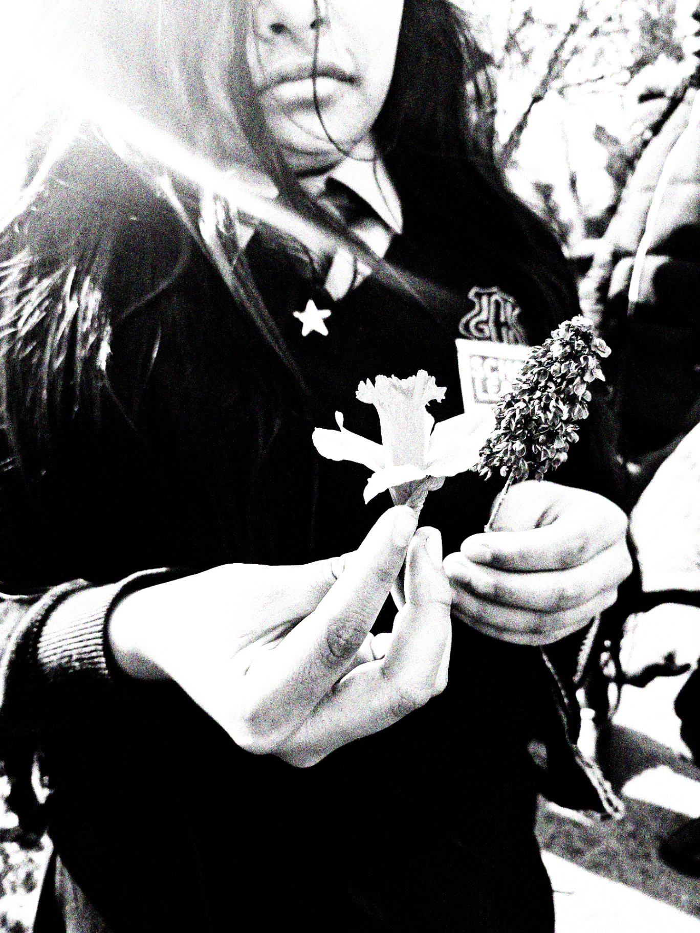 A child in school uniform holding a daffodil and a seedhead in cupped hands