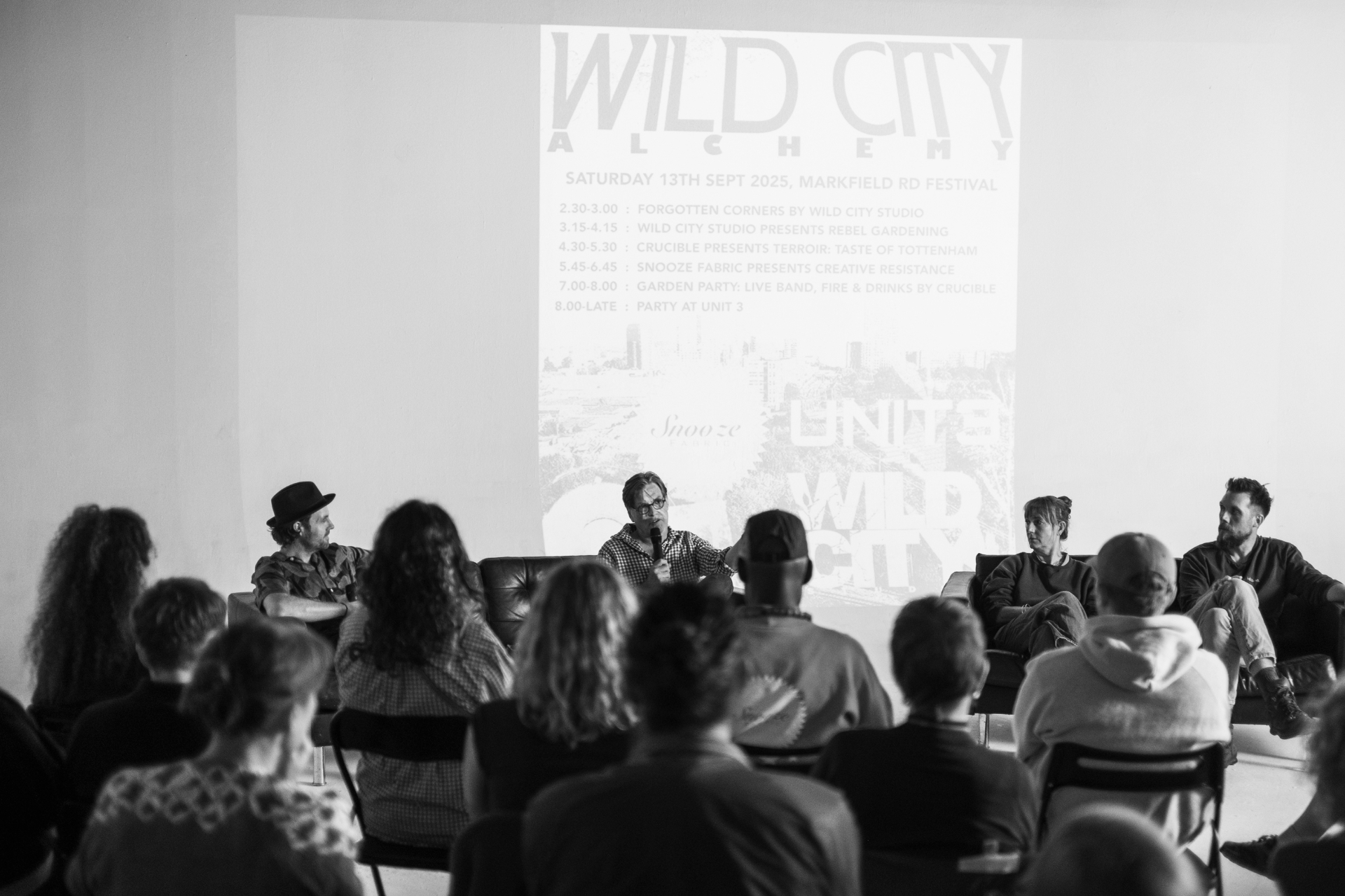Wild City Alchemy programme projected on the wall — the day's running order at Markfield Rd Festival 2025.