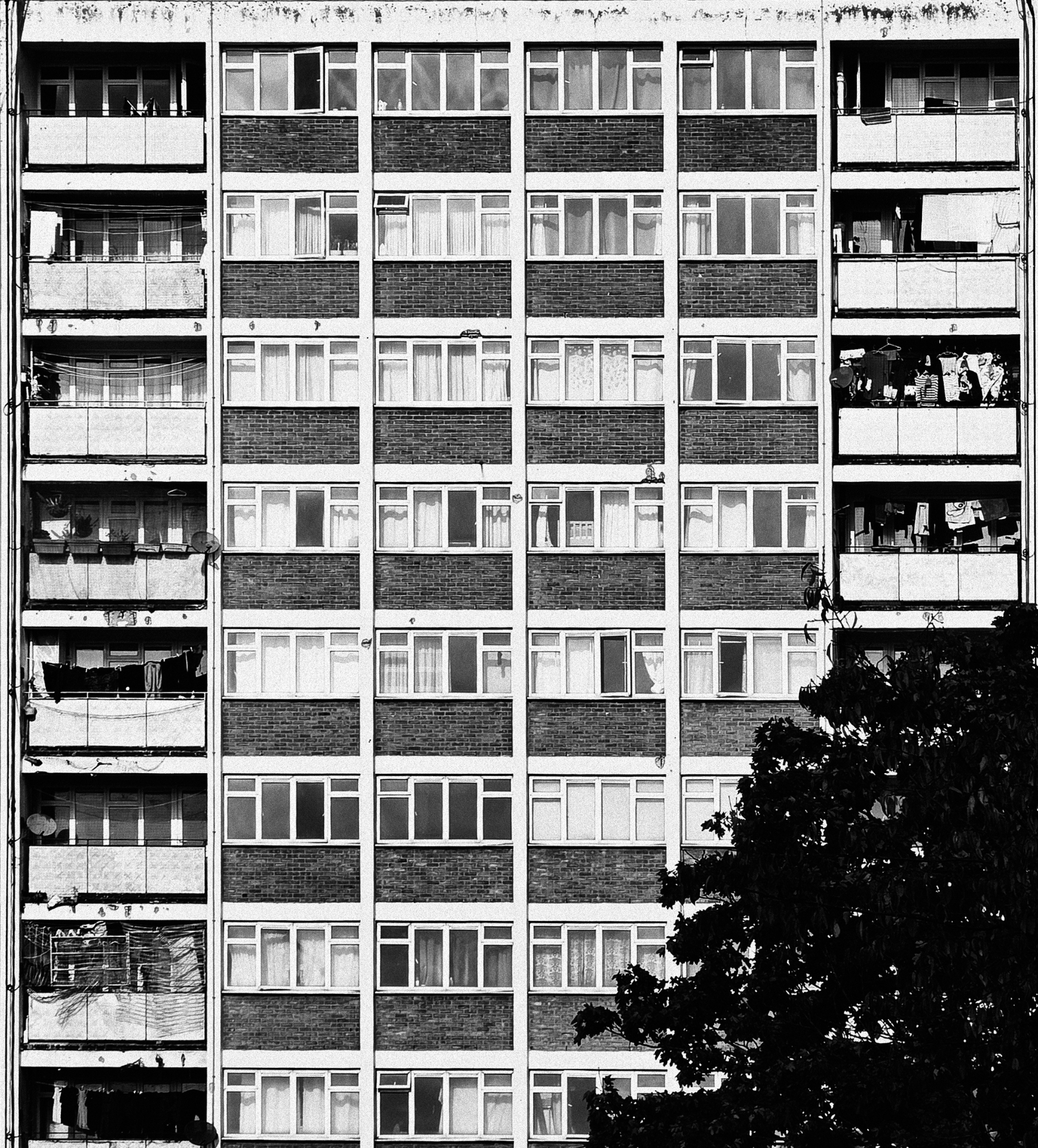 Black and white facade of a high-rise tower block with balconies and windows.