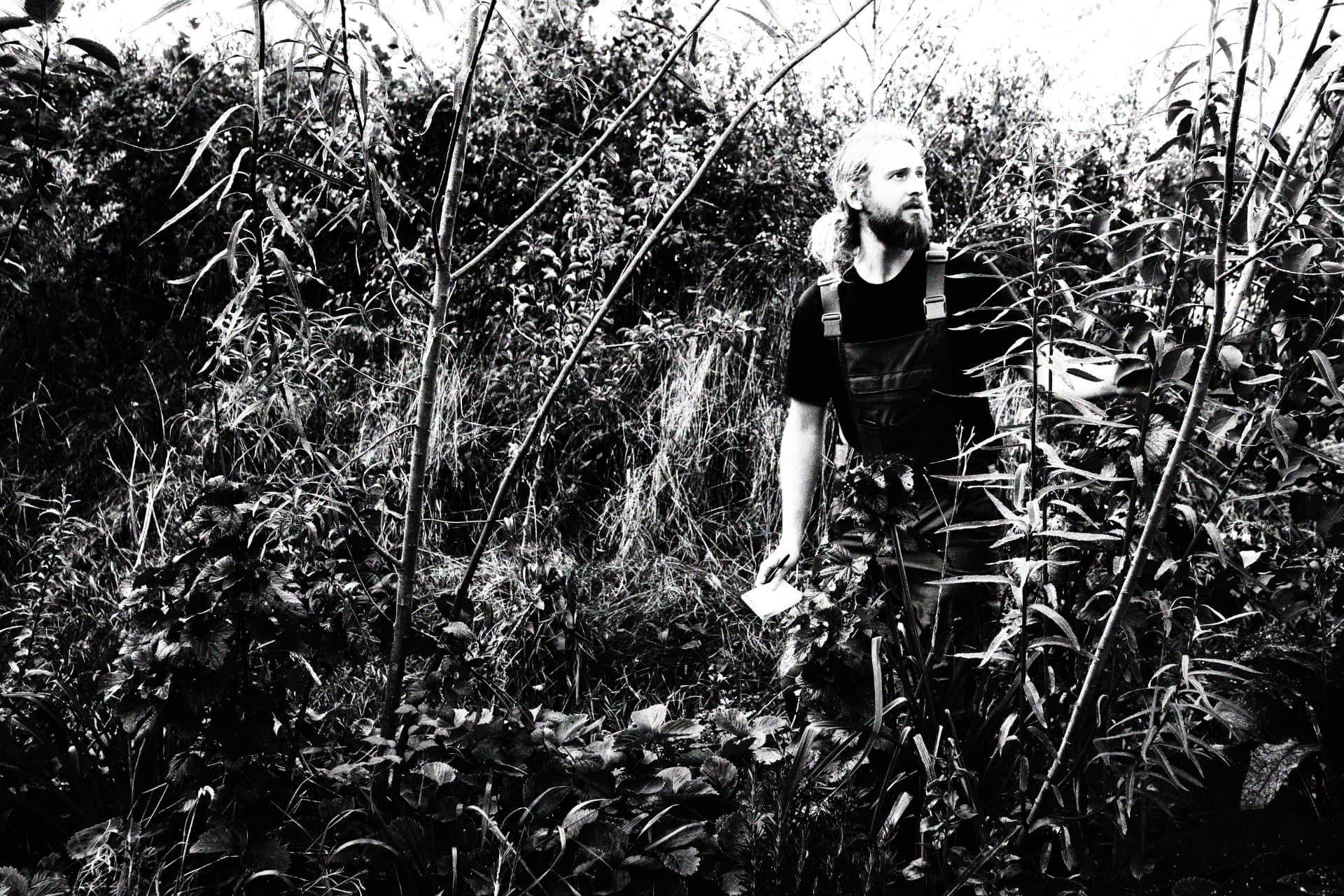 Jack Peppiatt of Birch Farm standing among dense planting, black and white