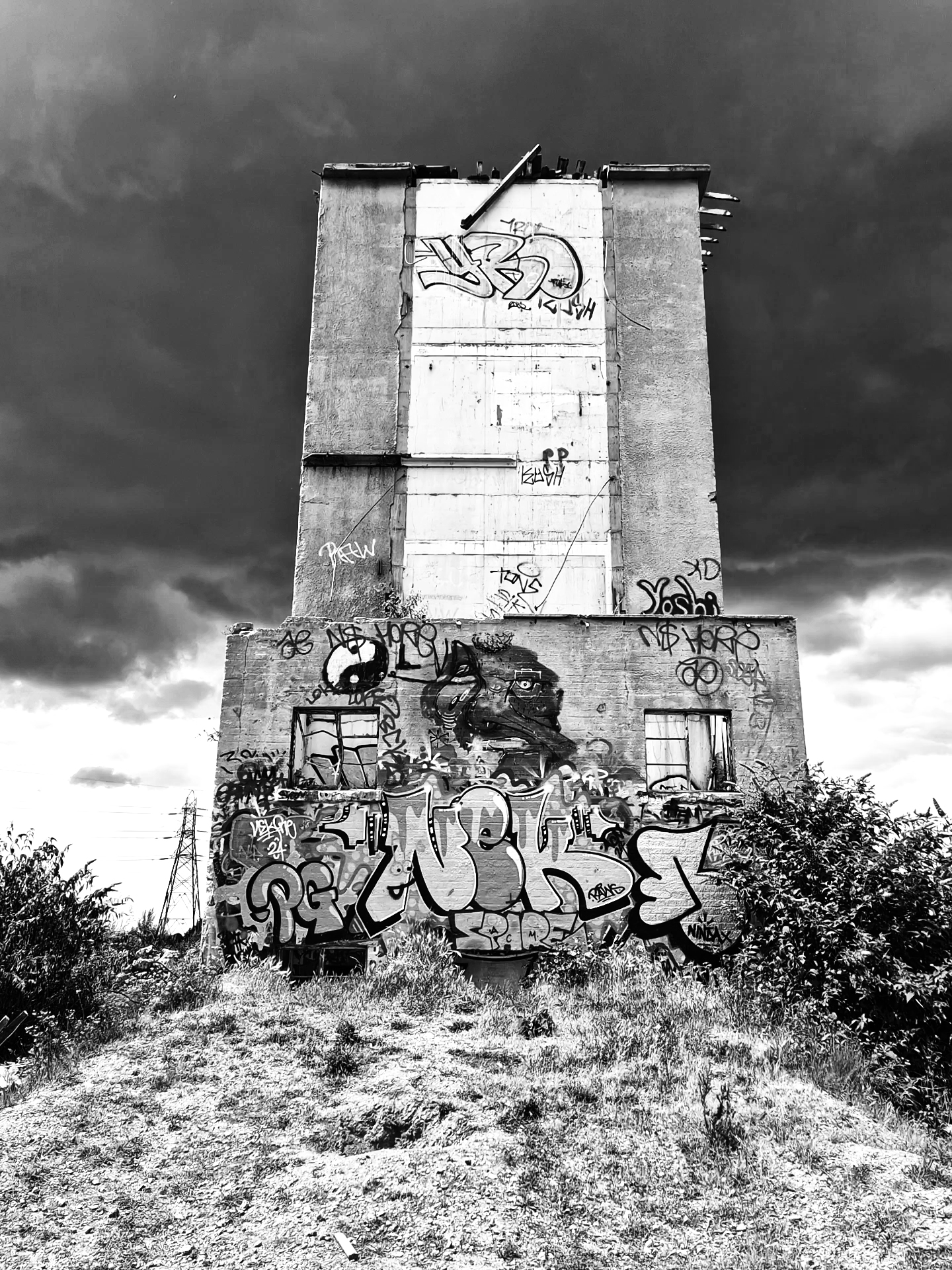 Graffiti-covered concrete tower under a stormy sky.