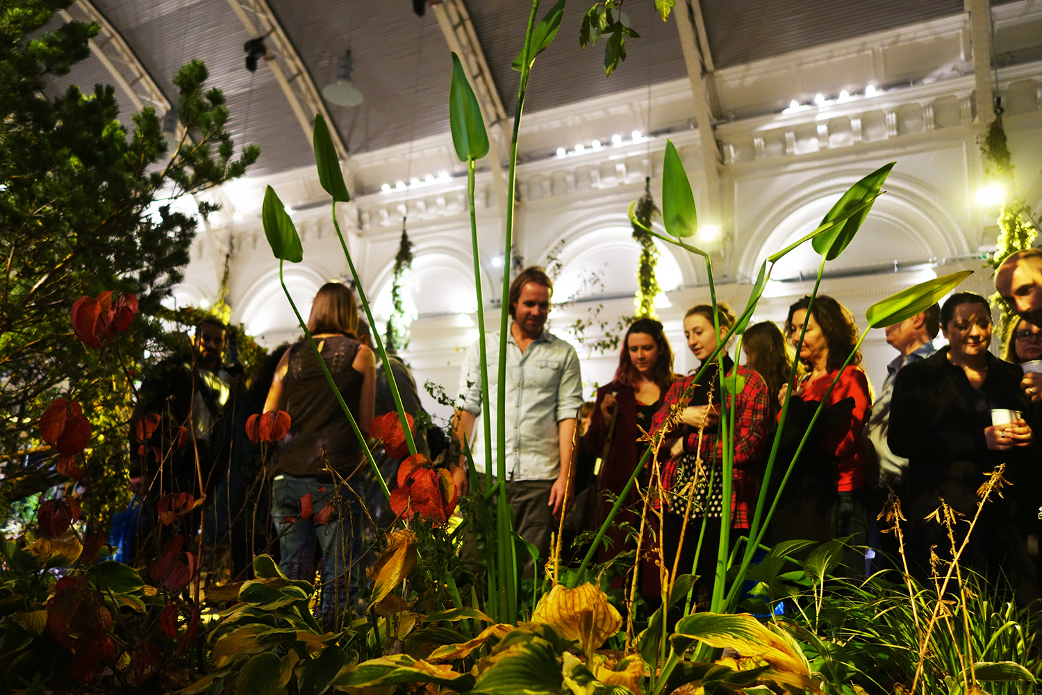 Visitors moving through the immersive planting beneath the hall's arches