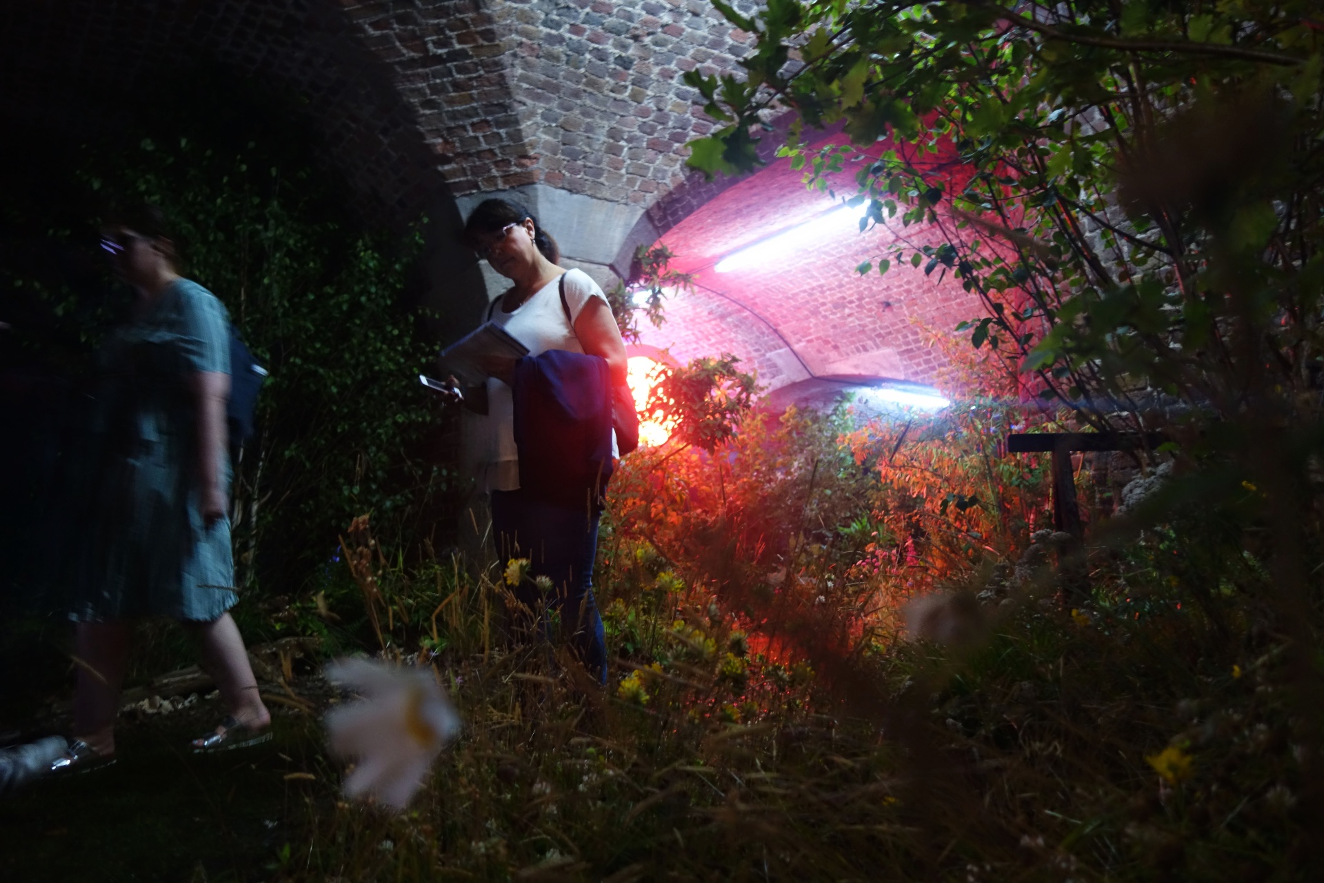 A visitor reads under red light beneath the brick vault