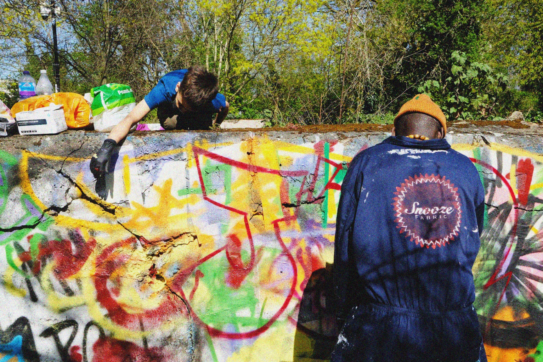 Two artists working together on a section of the wall.