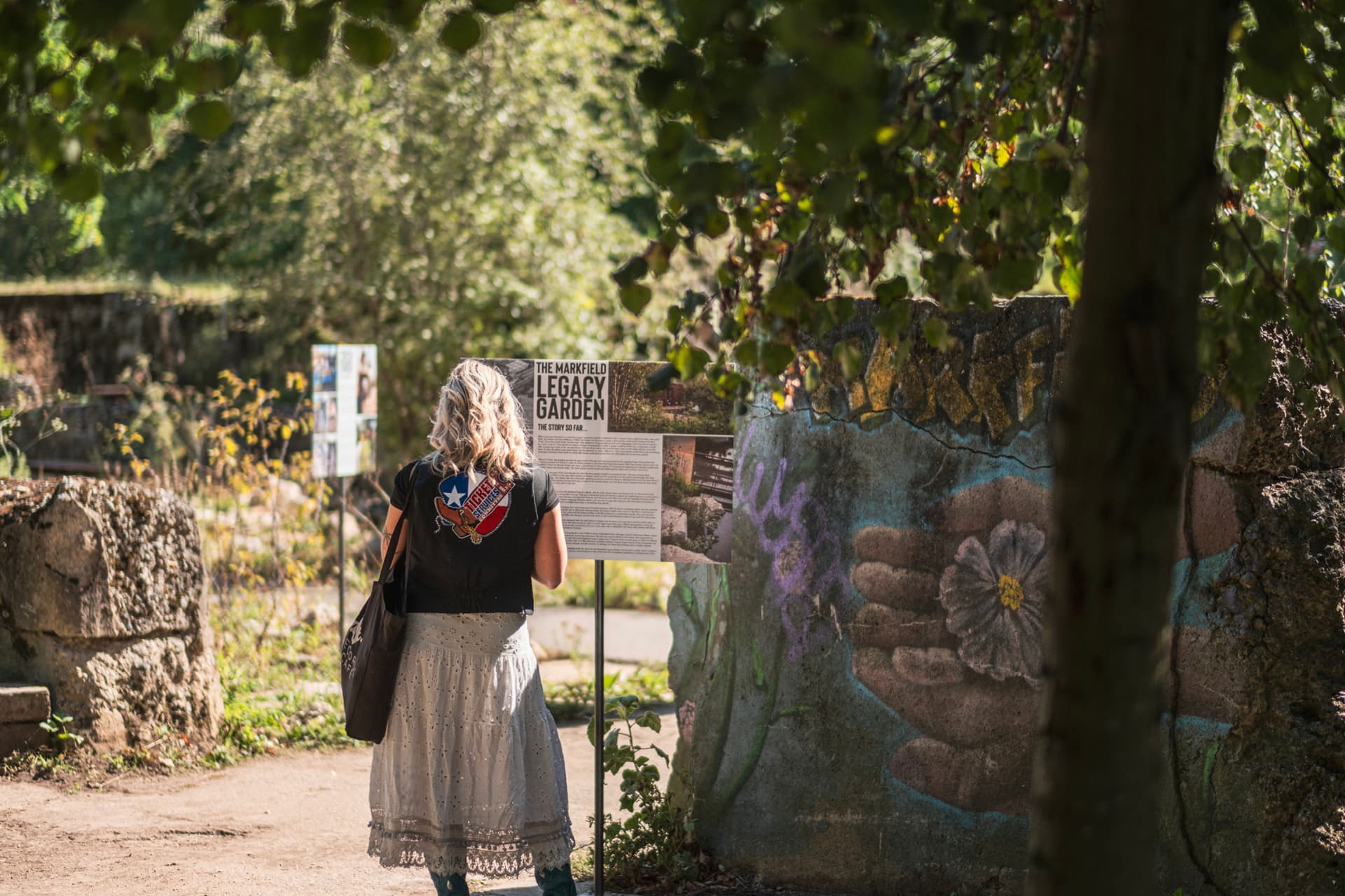 A visitor reading the Markfield Legacy Garden story board in the garden